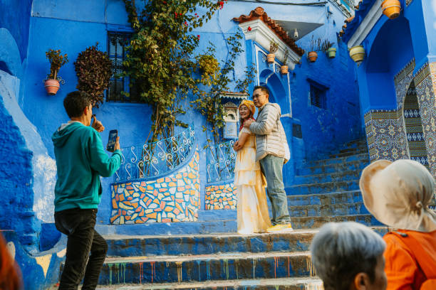 Chefchaouen, Morocco - February 10, 2025: A couple poses for a photo while exploring the vibrant streets of Chefchaouen, Morocco, surrounded by colorful blue walls and unique architecture, creating a picturesque travel memory.