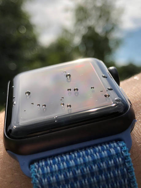 Apple watch on hand during rain with water drops on the turned off display under the sun rays