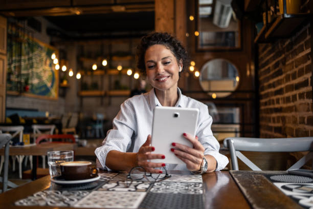 istock Mature woman enjoying a coffee shop and using a tablet while taking a break from work 2202534526