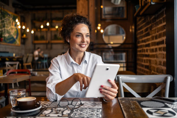 istock Mature woman enjoying a coffee shop and using a tablet while taking a break from work 2202534529