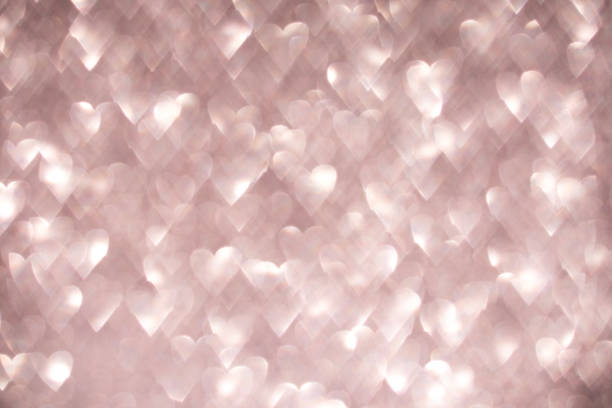 istock Soft glowing hearts create a romantic bokeh effect on a light pink background 2202534737