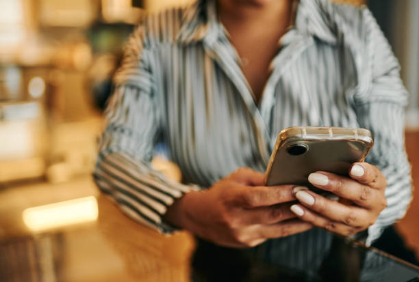 istock Woman texting using mobile phone on glass desk at home 2202535796
