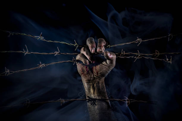 istock Bloody hand seeking freedom on barbed wire 2202536930