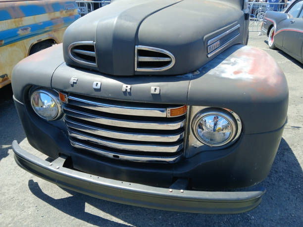 Restored ford f series pickup truck showcasing its classic grille and headlight Ericeira, Portugal, June 15, 2024, Close up of a vintage ford f series pickup truck, highlighting its restored chrome grille, headlight, and weathered body, parked at a car show distressed rusty vintage pickup truck close up detail stock pictures, royalty-free photos & images