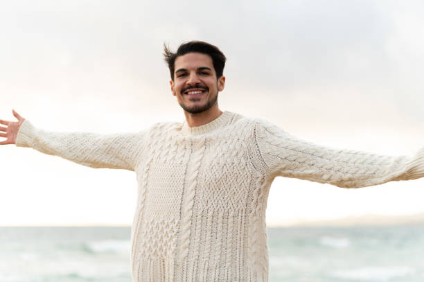 istock Man opening arms at the beach enjoying freedom 2202538034
