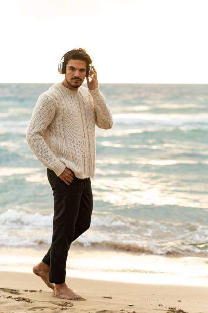 istock Man listening to music while walking on the beach 2202538053