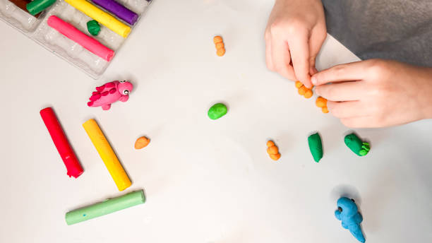 istock Creative children's modeling from plasticine at home. The child plays with plasticine developing the motor skills of the hands. The child is sculpting a dinosaur. High quality photo 2202542974