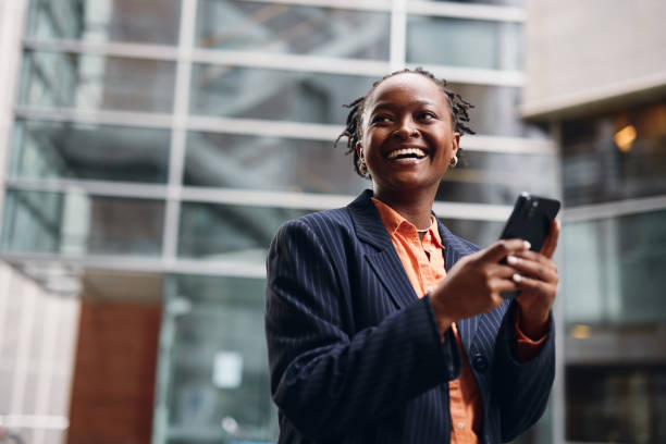 istock Smiling businesswoman using smartphone in front of office building 2202543063