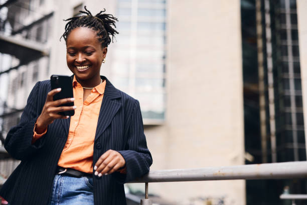 istock Smiling black businesswoman using smartphone in urban setting 2202543139