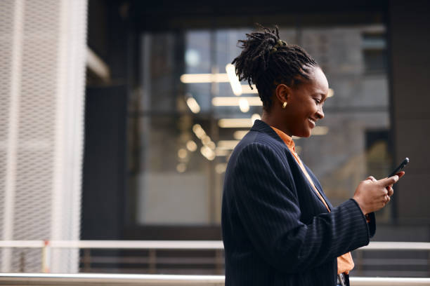 istock Smiling businesswoman using smartphone outside office building 2202543183