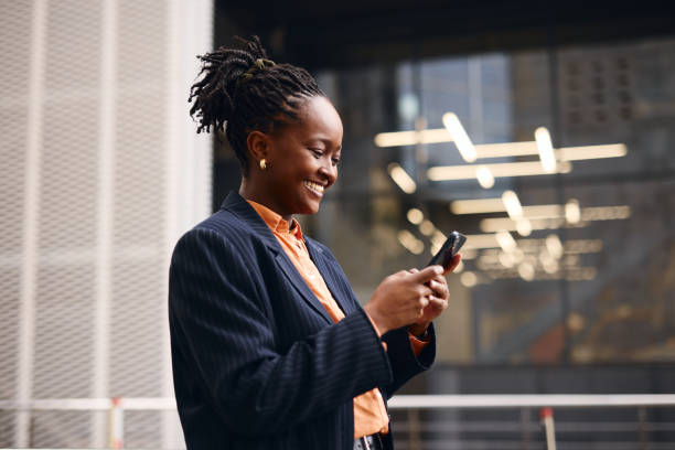 istock Smiling businesswoman using smartphone outside office building 2202543192