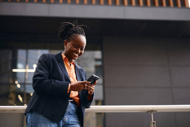 istock Smiling businesswoman using smartphone outside office building 2202543211