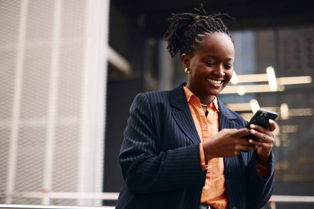 istock Smiling businesswoman using smartphone outside office building 2202543233