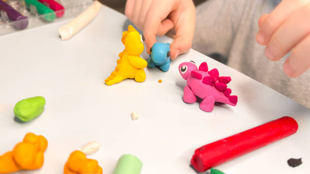 istock Creative children's modeling from plasticine at home. The child plays with plasticine developing the motor skills of the hands. The child is sculpting a dinosaur. High quality photo 2202543309