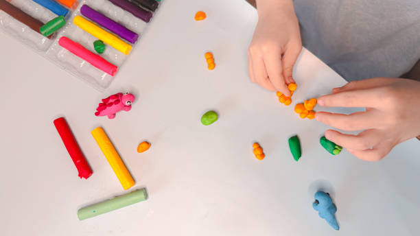 istock Creative children's modeling from plasticine at home. The child plays with plasticine developing the motor skills of the hands. The child is sculpting a dinosaur. High quality photo 2202543391