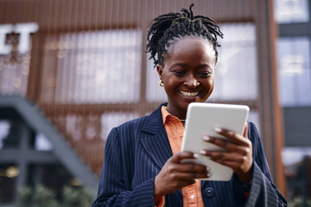 istock Smiling black businesswoman using digital tablet in urban setting 2202543446