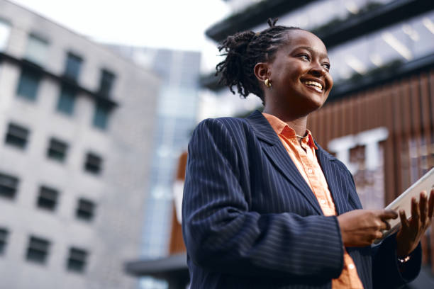 istock Smiling black businesswoman using digital tablet in city 2202543505