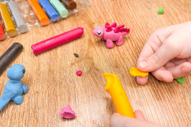 istock Creative children's modeling from plasticine at home. The child plays with plasticine developing the motor skills of the hands. The child is sculpting a dinosaur. High quality photo 2202543558