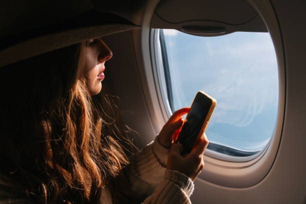 istock Tourist with a hat taking photos through the airplane window 2202546468