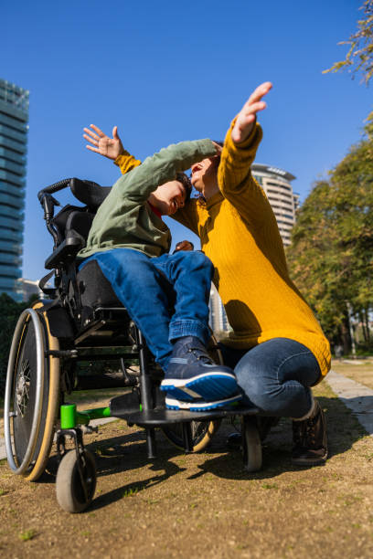 istock Mother and disabled son playing together in a city park 2202551949