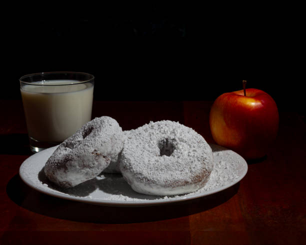 istock Powdered Doughnuts with Milk and an Apple on a Wooden Table 2202556092