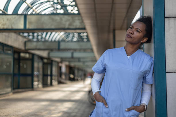 istock Tired nurse leaning against wall outside hospital taking break 2202559162