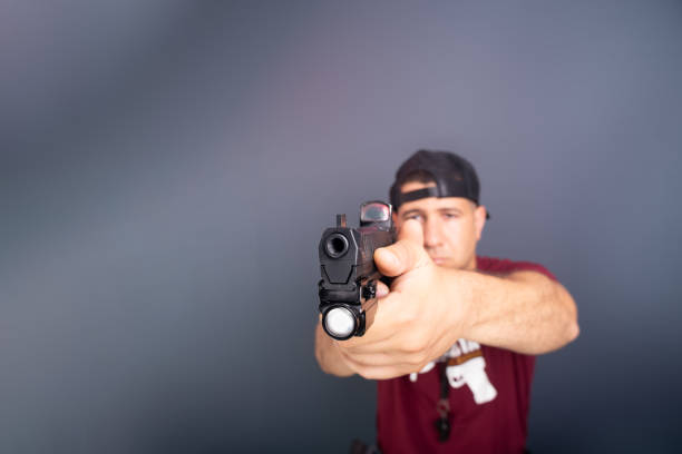 Studio portrait of a shooting instructor pointing a firearm to the side. Sport practice. Brazil