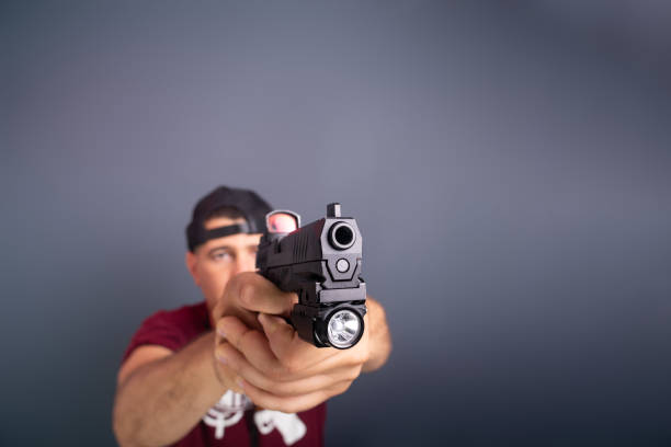 Studio portrait of a shooting instructor pointing a firearm to the side. Sport practice. Brazil