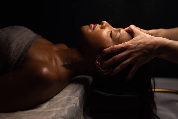 istock Experienced massage therapist stimulating acupoint on woman face. 2202563917
