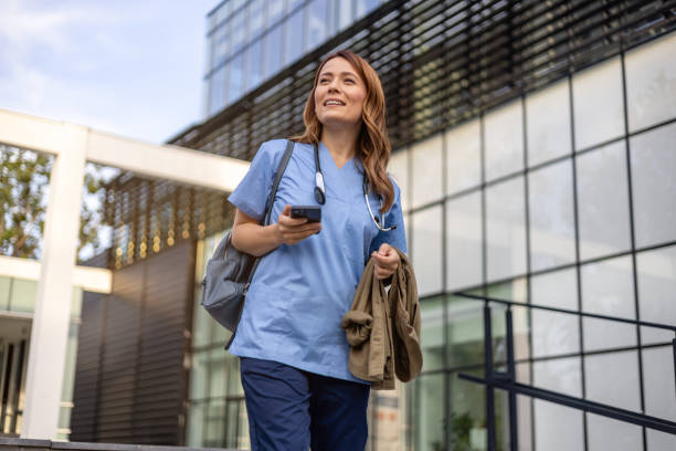 istock Smiling doctor walking outside hospital using smartphone 2202567003
