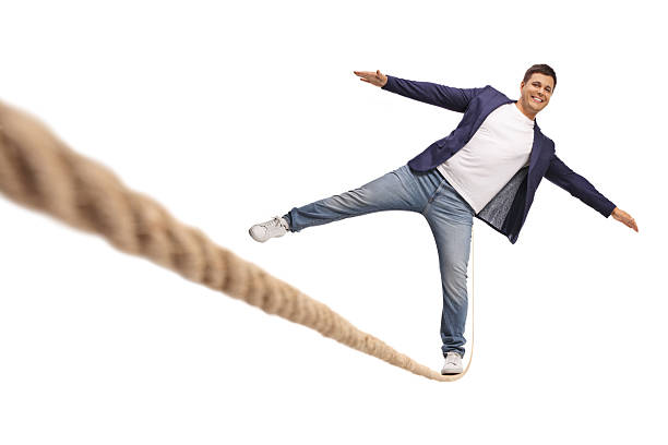 Young man trying to balance on a tightrope isolated on white background