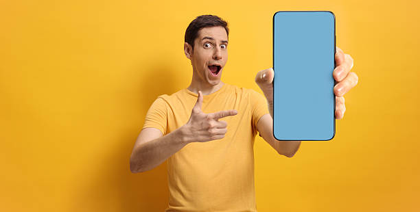 istock Surprised man pointing at a smartphone with blue screen 2202567371
