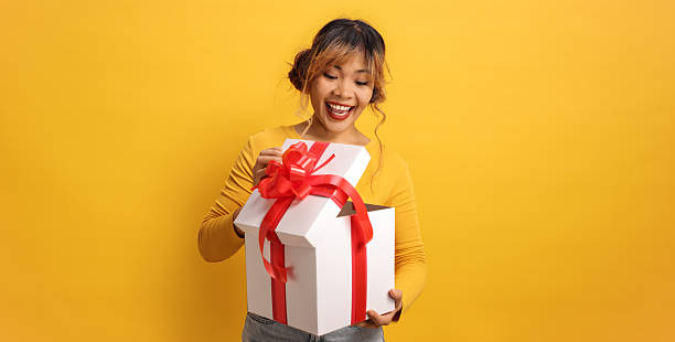 istock Cheerful young asian woman opening a present 2202568197