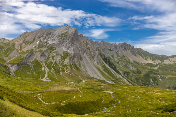 Tour du Mont Blanc beautiful alpine scenic view. Landscape of the summer Alps mountains with pocky peaks, blue ice glacier, green grass and blooming flowers. Alps in Italy and France hiking and trek