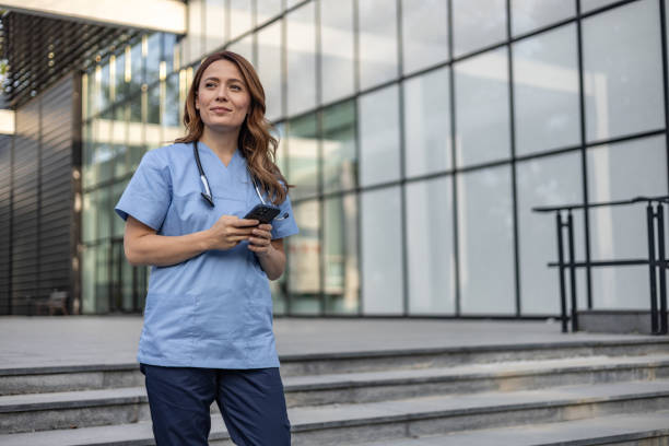 istock Confident female doctor using smartphone outside hospital building 2202568667