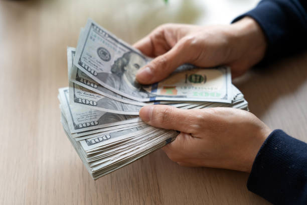 istock Businesswoman counting hundred dollar bills 2202574749