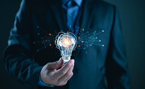 istock Businessman holding illuminated lightbulb, idea, innovation and inspiration with glowing virtual brain, smart intelligent creativity with bulbs, Motivation and innovation concept 2202576997