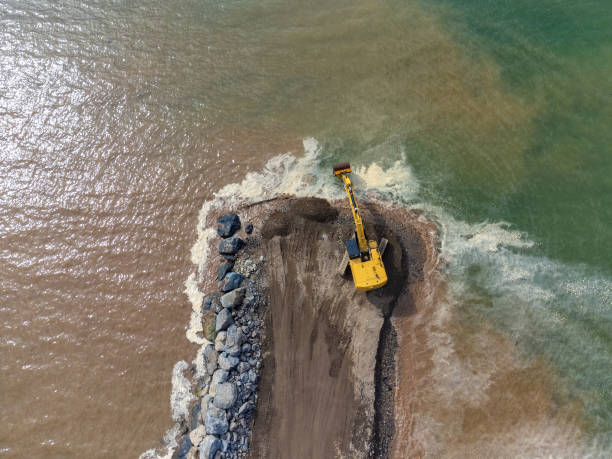 istock Drone view of a working yellow excavator on the seashore, river or dam. 2202585442