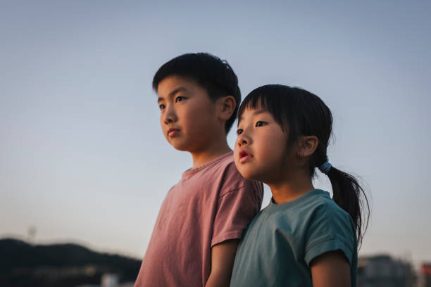 Asian brother and sister relaxed in the beach at sunset time.
