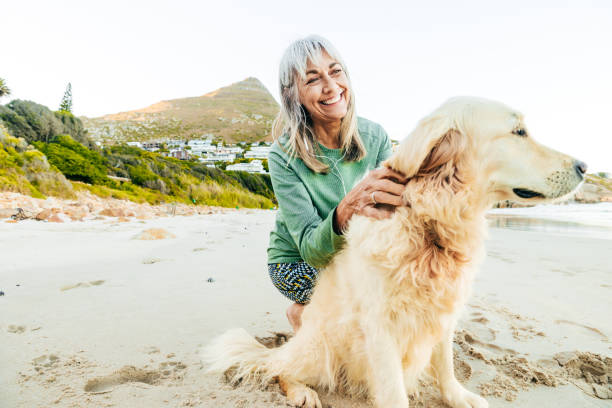 istock Mature women on the beach with her dog 2202586632