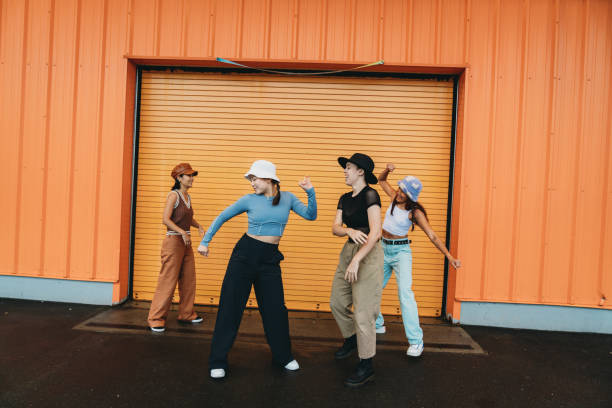 istock Cool dancers are having fun dancing against an orange wall 2202587126