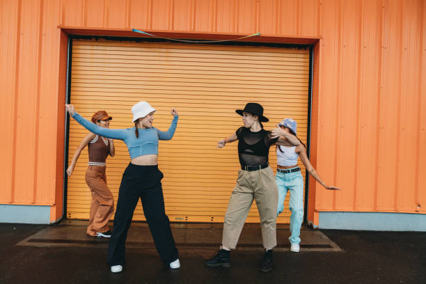istock Cool dancers are having fun dancing against an orange wall 2202587133