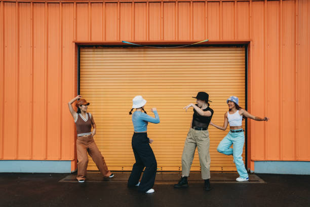 istock Cool dancers are having fun dancing against an orange wall 2202587146