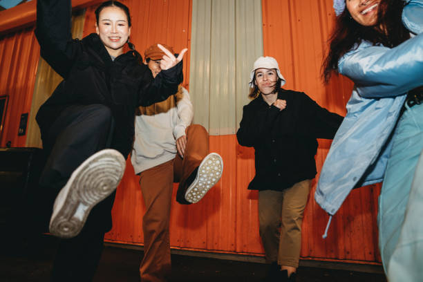 istock Cool dancers are having fun dancing against an orange wall 2202587175