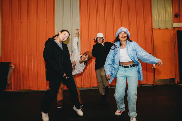 istock Cool dancers are having fun dancing against an orange wall 2202587188