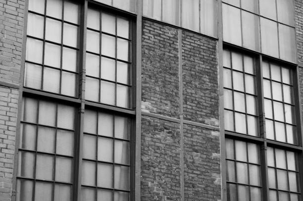 Large industrial windows alternate with sections of brick wall in this black and white architectural study