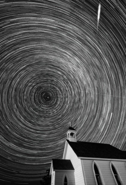 Star trails rotating over a country church at night stock photo