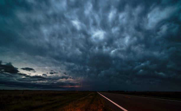 istock Approaching storm threatens rural Midwest. Dramatic clouds loom over empty Kansas highway as night falls. 2202589103