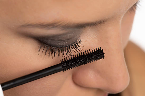 istock beautiful woman applying mascara on a white background 2202589871