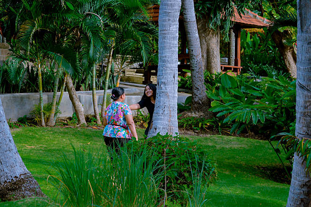 istock Two Women Interacting in a Lush Garden Setting with Palm Trees 2202607272
